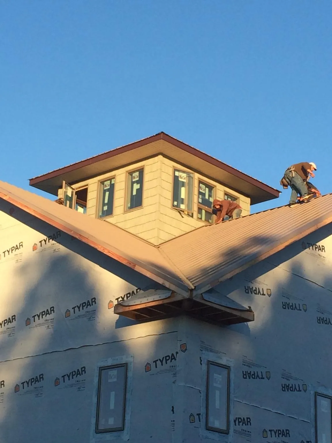 Roofers working around a rooftop cupola on a new metal roof at sunset — Roof Waterproofing in Sterling by Roofing Brothers